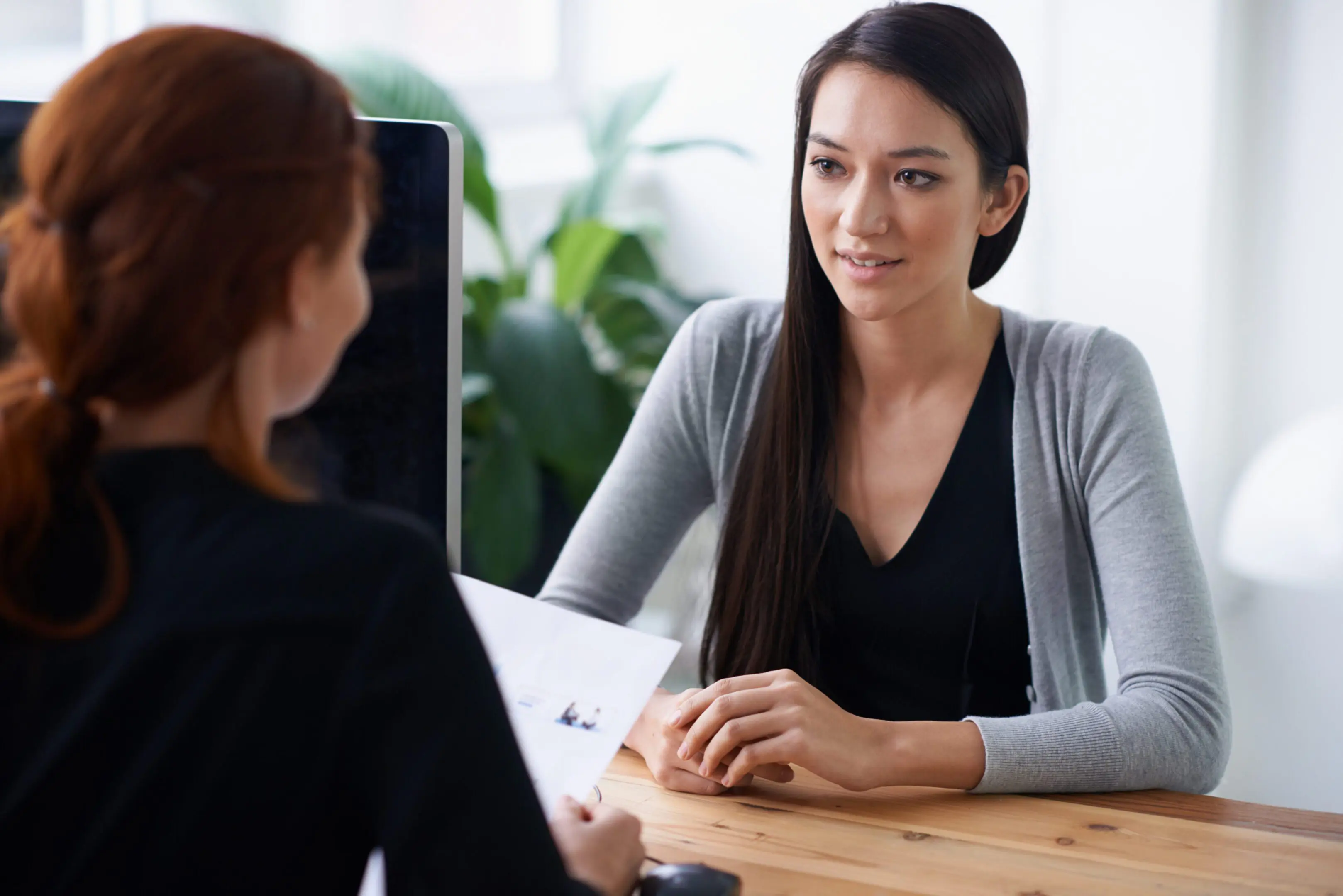 Two women engaged in a professional discussion at a desk.