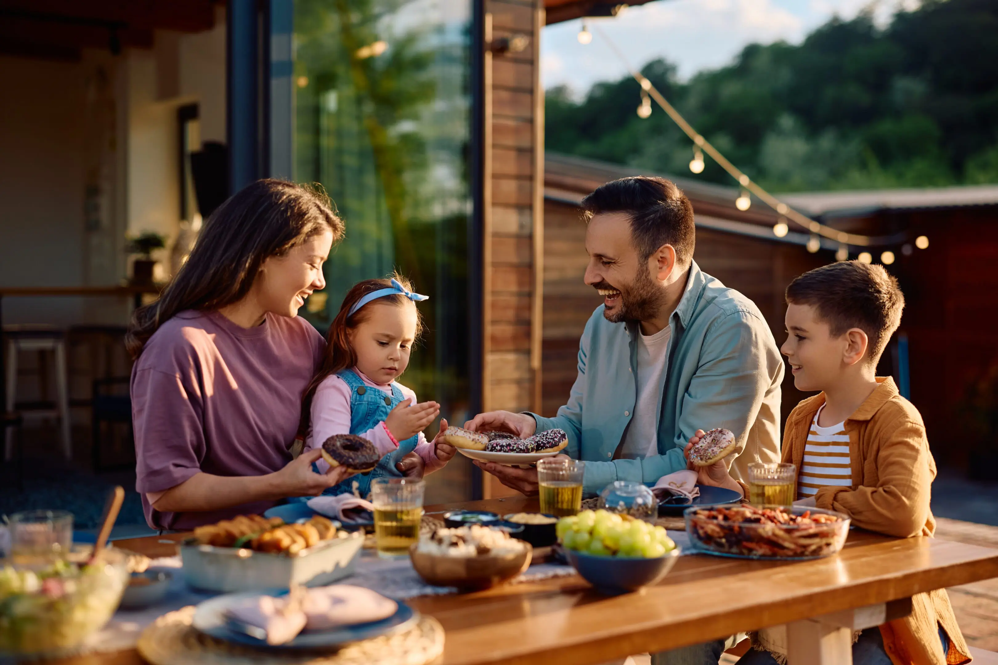 Family enjoying dinner together outdoors with smiles and joyful interaction.